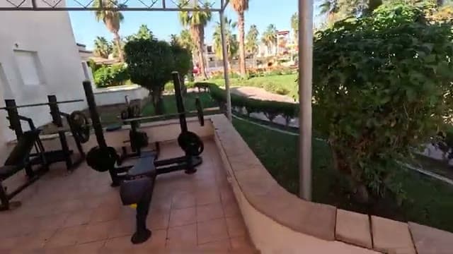 L'angolo palestra all'aperto dell'Amphoras Aqua con la panca e i pesi, affacciato sui giardini fra le due piscine