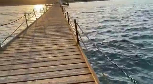 Il pontile in legno dell'Amwaj Hotel al tramonto, con le corde laterali e il mare che si scurisce ai lati