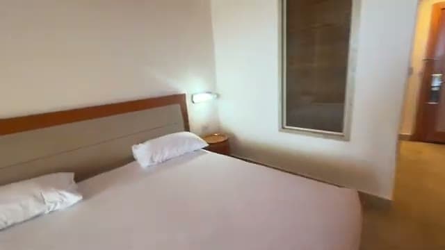 Il letto della camera del Barcelo Sharm, semplice ed essenziale, con la testiera in legno e i comodini nei toni terra di Siena
