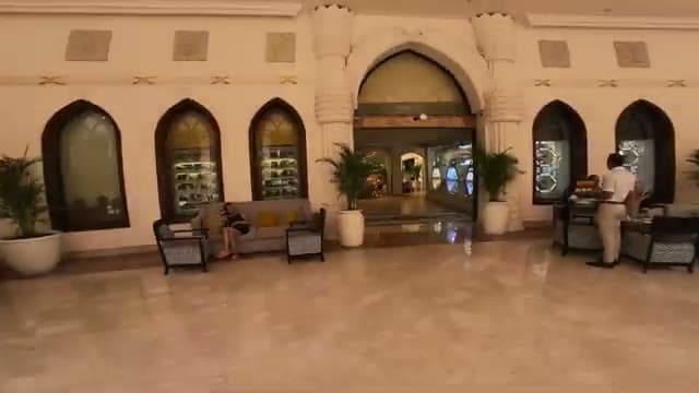 La zona lounge accanto alla reception del Caribbean World Hurghada, con divano, piante e le vetrine dei negozietti incastonate nelle arcate