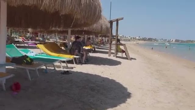 La lunga fila di ombrelloni di paglia e lettini colorati sulla spiaggia sabbiosa del Caribbean World Hurghada, con la torretta del bagnino e la costa che si perde in lontananza