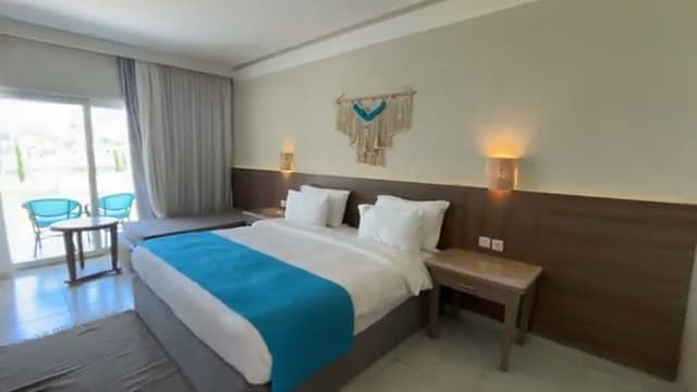 La camera del Casa Blu con il letto grande, il copriletto azzurro, i decori boho chic sopra la testata e la porta finestra sul balcone
