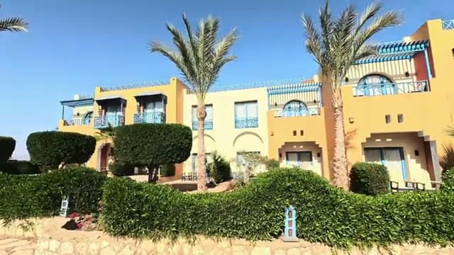 Gli edifici gialli del Faraana Heights fra palme e siepi curate, visti dal vialetto interno
