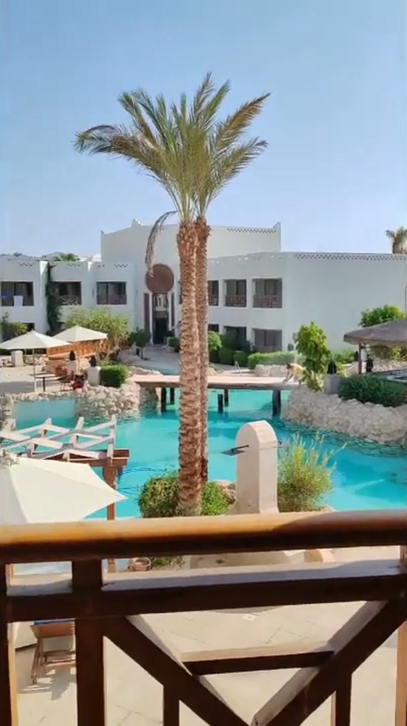 Il balcone di una camera del Ghazala Gardens con vista sulla piscina, la palma e le palazzine bianche del villaggio