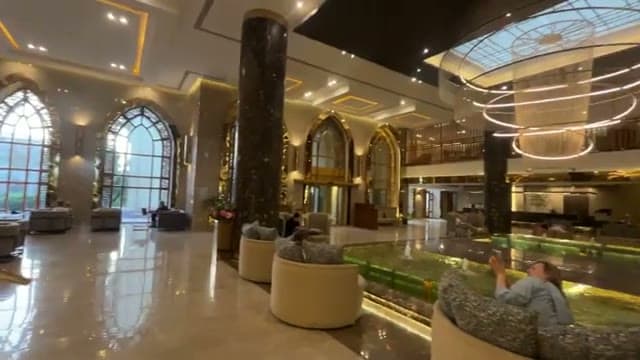 La lobby di The Grand Hotel con le grandi vetrate ad arco, le colonne in marmo e la fontana interna