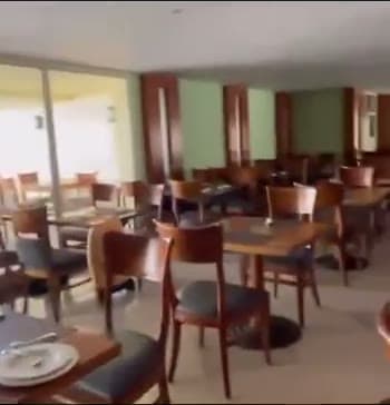 La sala del ristorante self-service dell'Hilton Sharks Bay, con i tavoli in legno apparecchiati e la vetrata sul giardino
