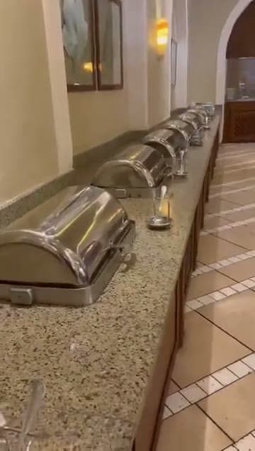 La fila dei vassoi caldi del buffet del Jaz Mirabel Beach lungo il bancone in granito