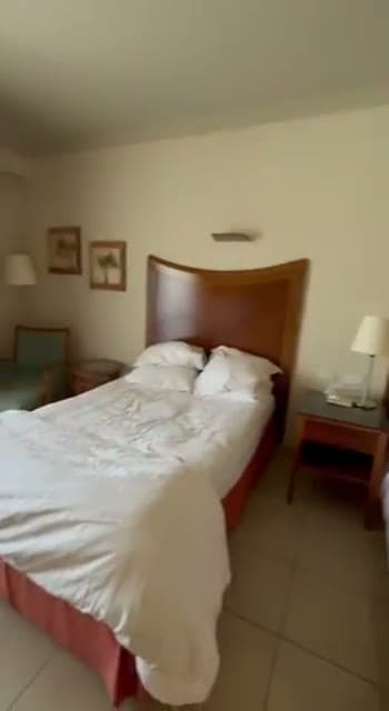 La camera del Naama Bay Promenade Resort con il letto rifatto, il comodino e la poltrona vicino alla finestra