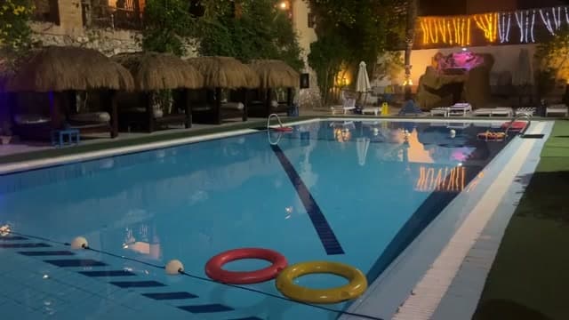 La piscina del Naama Blu illuminata di sera, con le luci sotto i gazebo in paglia