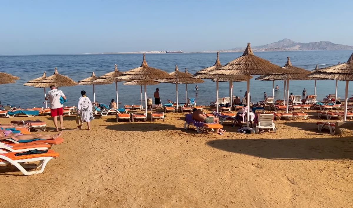 La spiaggia del Nubian Village con ombrelloni di paglia, sabbia dorata e bagnanti in acqua
