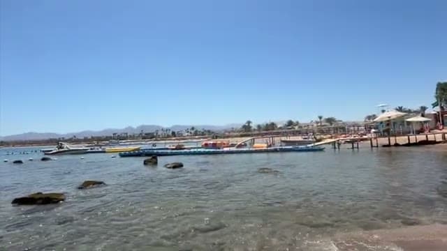 La spiaggia sabbiosa di Naama Bay vista dalla riva, con il pontile delle attività e le montagne sullo sfondo