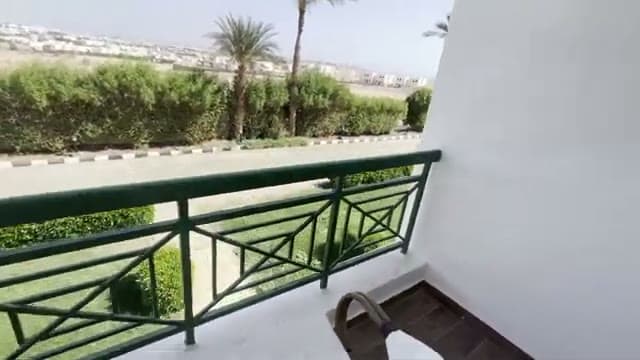 La vista dal balcone della camera del Panorama Naama Heights: la ringhiera verde, i giardini e la strada sotto la collina