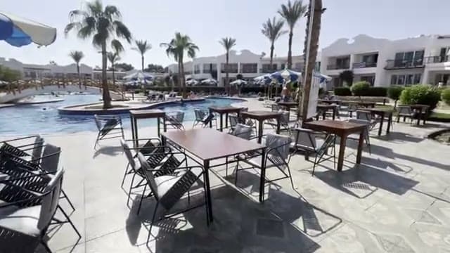 I tavoli della terrazza esterna del Panorama Naama Heights affacciati sulla piscina, con le palme e gli edifici bianchi sullo sfondo