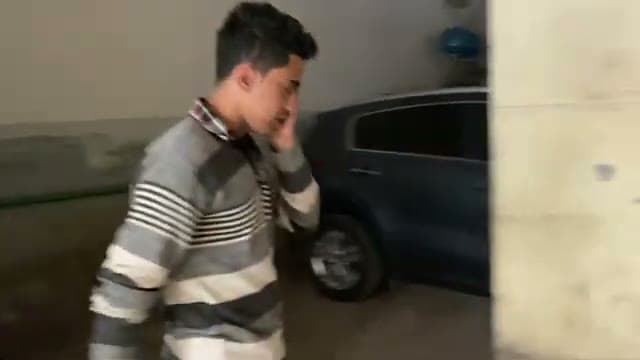 Un ragazzo addetto al parcheggio privato accanto a un'auto in un garage del Cairo