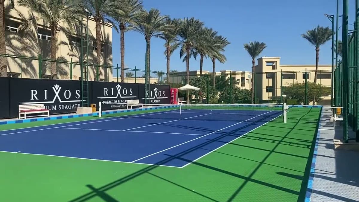 Il campo da tennis del Rixos Premium Seagate, con il logo dell'hotel e le palme della zona di Nabq alle spalle
