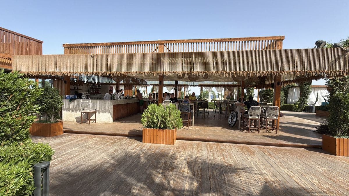 Il bar sulla spiaggia del Rixos Radamis, con il tetto di paglia, la pedana in legno e le piante