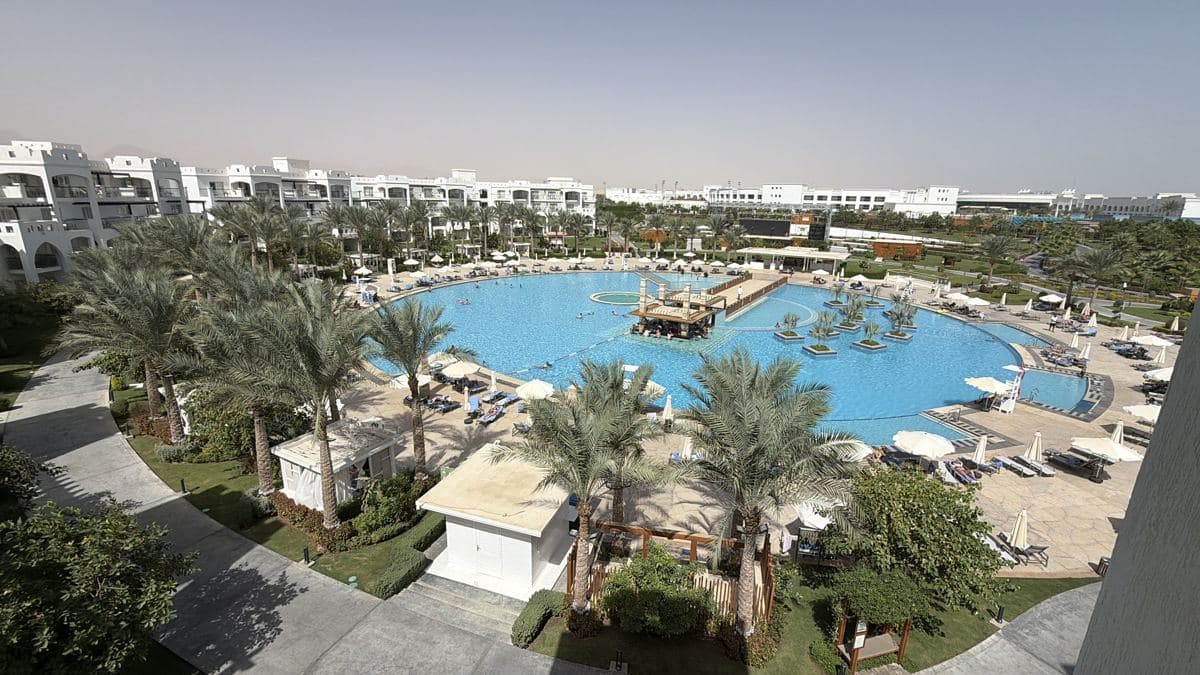 La piscina centrale del Rixos Blue Planet vista dall'alto, con le palme, i lettini e gli edifici delle camere intorno