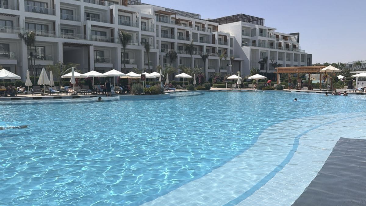 La piscina del Rixos Radamis con gli ombrelloni bianchi, i lettini e gli edifici delle camere intorno