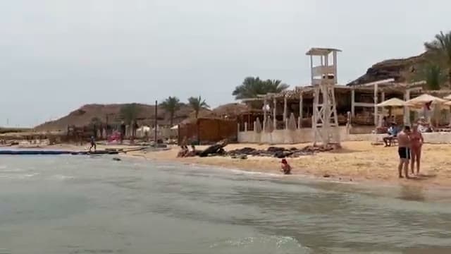 La riva sabbiosa del Sinbad Beach con la torretta del bagnino e pochissime persone in acqua