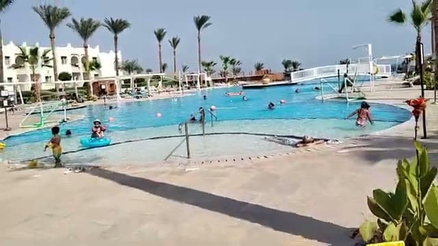 La piscina principale del Sunrise Diamond con i bagnanti, le palme e il mare sullo sfondo