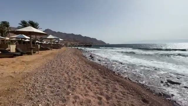 La riva sassosa della spiaggia del Tropitel Dahab Hotel, con le montagne del Sinai e il mare mosso dal vento