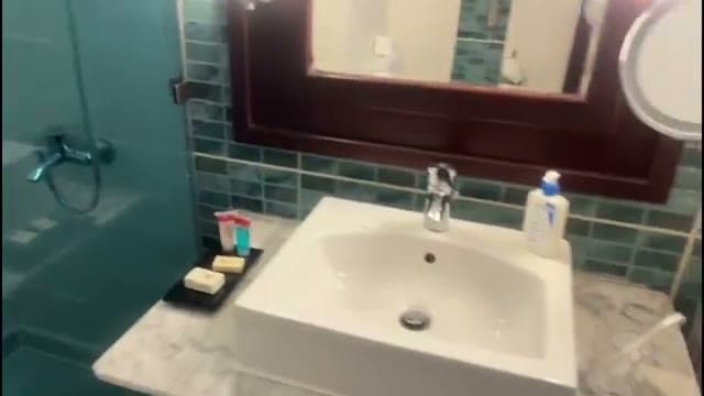 Il bagno della camera all'Xperience Sea Breeze: piastrelle turchese acquamarina, lavandino con specchio e doccia aperta