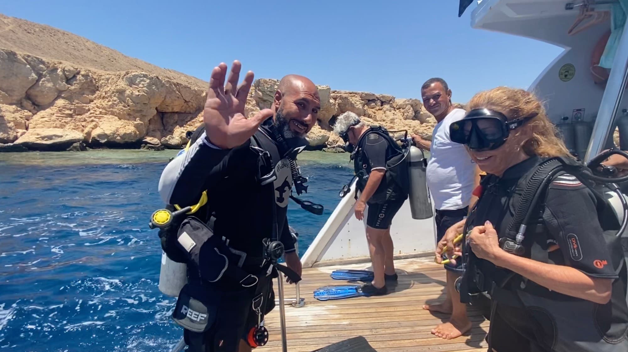 Subacquei pronti a entrare in acqua dalla piattaforma di poppa, davanti a una parete rocciosa del Sinai