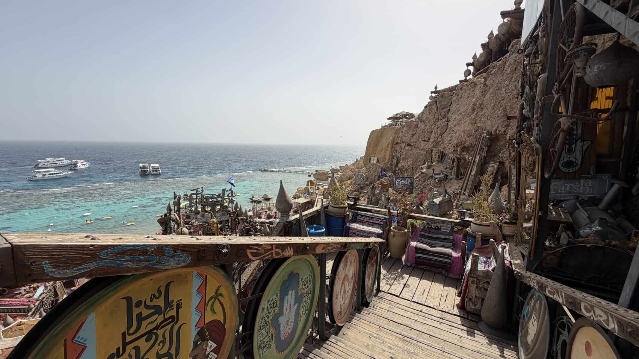 La spiaggia del Farsha sulla baia di Temple, con le barche colorate, la scogliera decorata e il Mar Rosso davanti