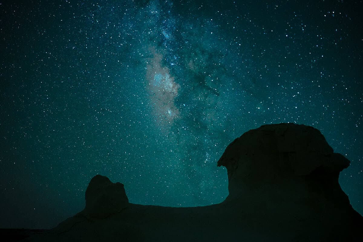 La Via Lattea si estende sopra due formazioni rocciose buttes silhouette nel deserto notturno