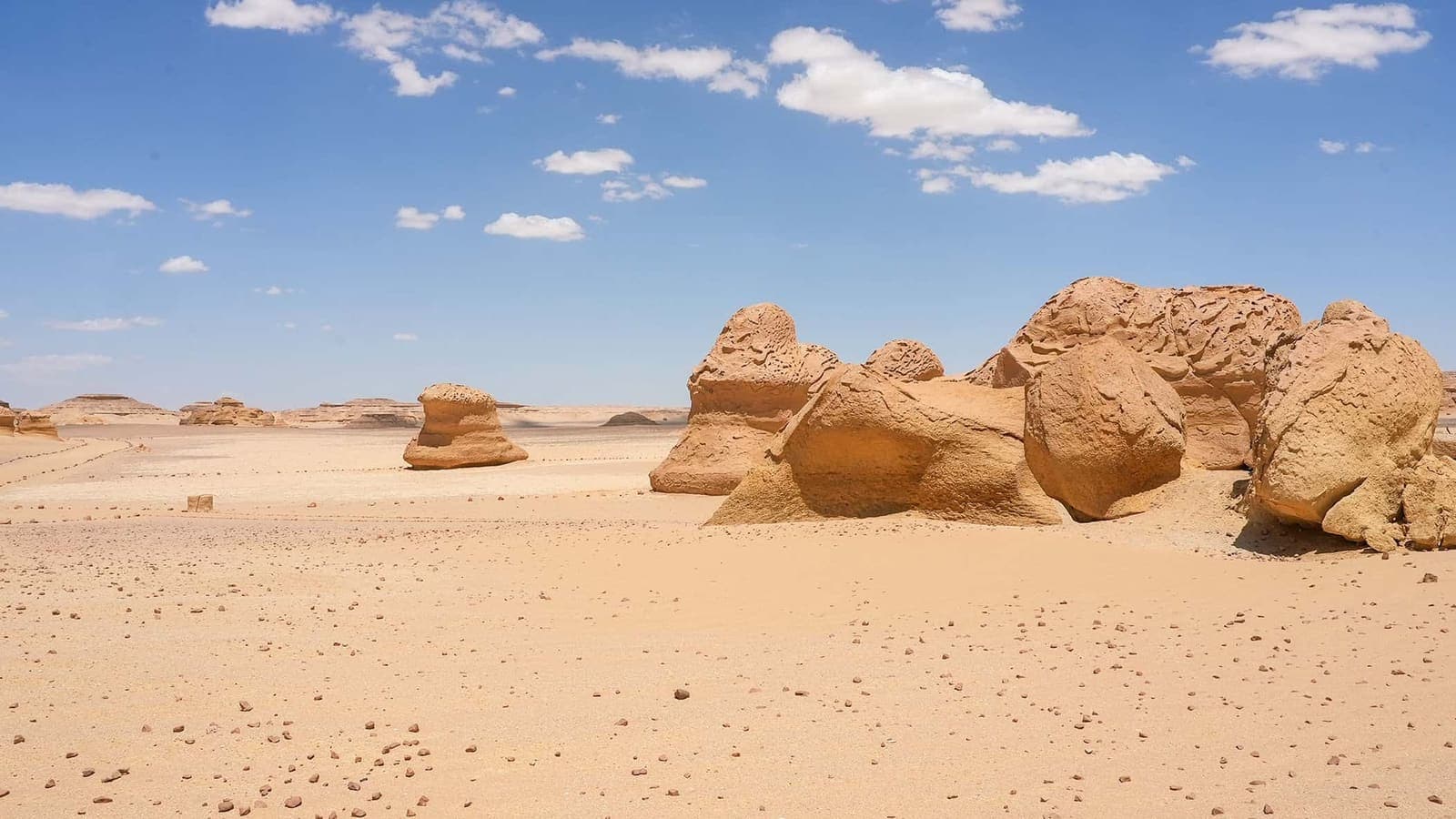 Formazioni rocciose di arenaria nel deserto egiziano con sabbia dorata e cielo azzurro