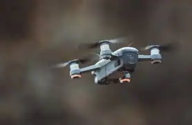 Un drone grigio e nero in volo con quattro eliche, ripreso da vicino su sfondo sfocato