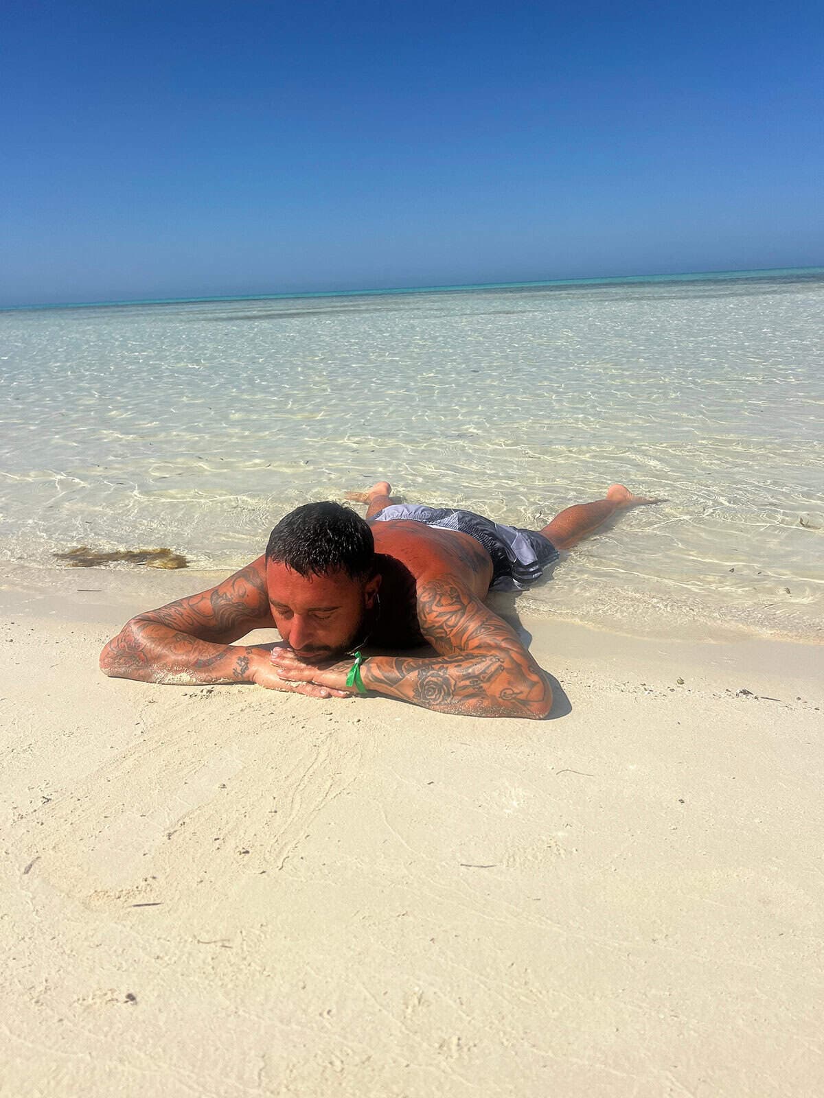 giovane in costume si rilassa sulla sabbia all' isola che non c' e'