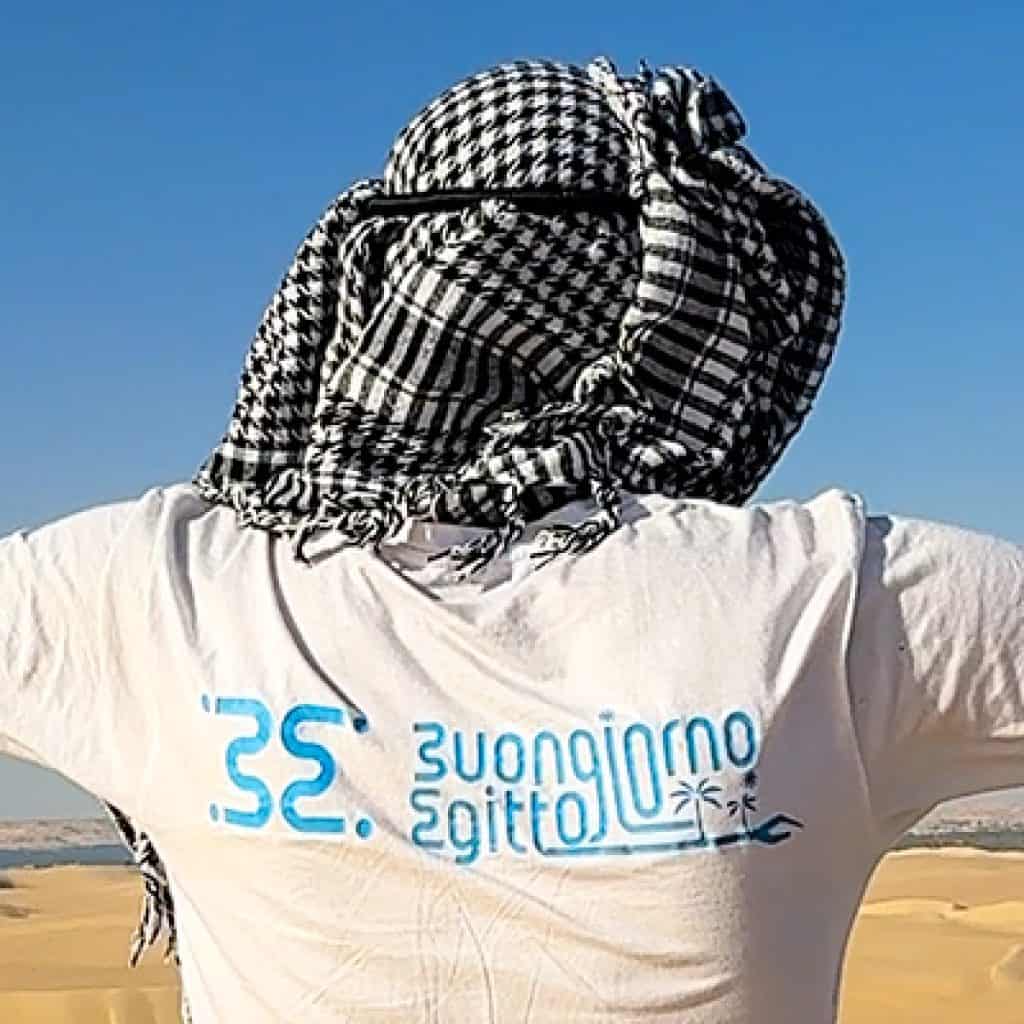 guida buongioro egitto con le braccia aperto, indossa un tipico velo arabo e deserto e laghi sullo sfondo