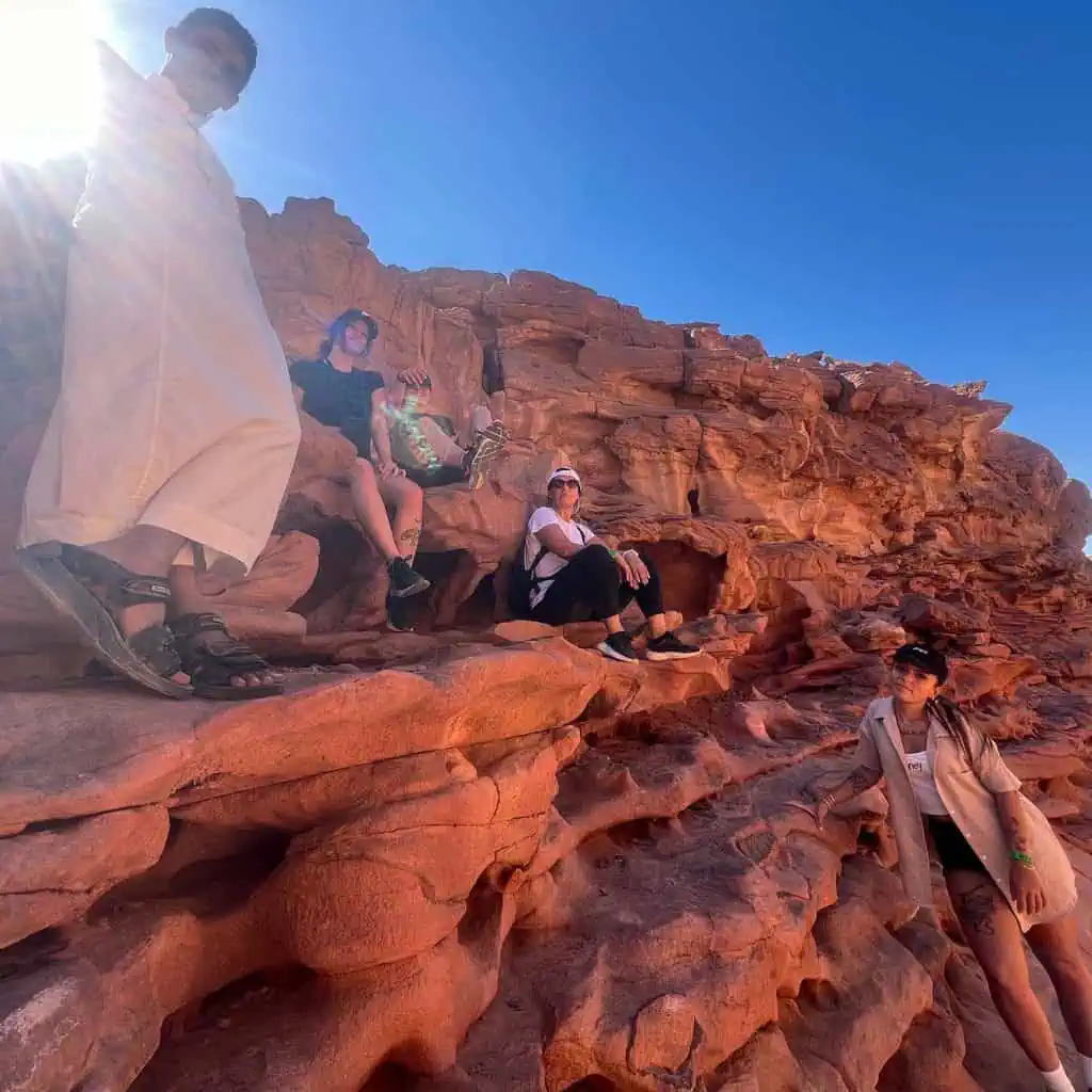 giovani donne con guida beduina in posa al canyon rosso
