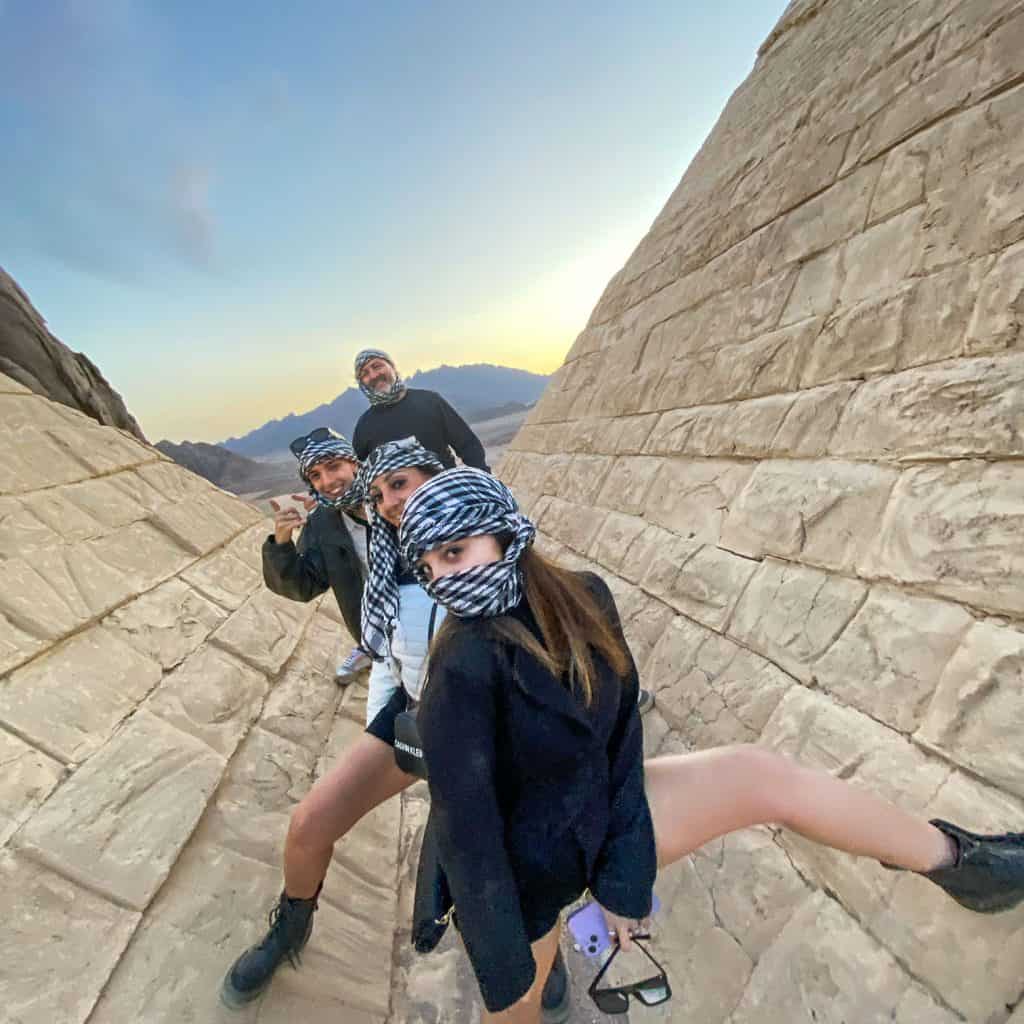 famiglia poggia le gambe sulle piramidi in miniatura del piccolo egitto durante l' escursione in quad a sharm