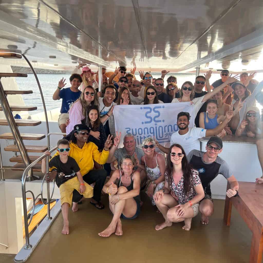 gruppo di persone sorridenti in barca con guida e bandiera di buongiorno egitto