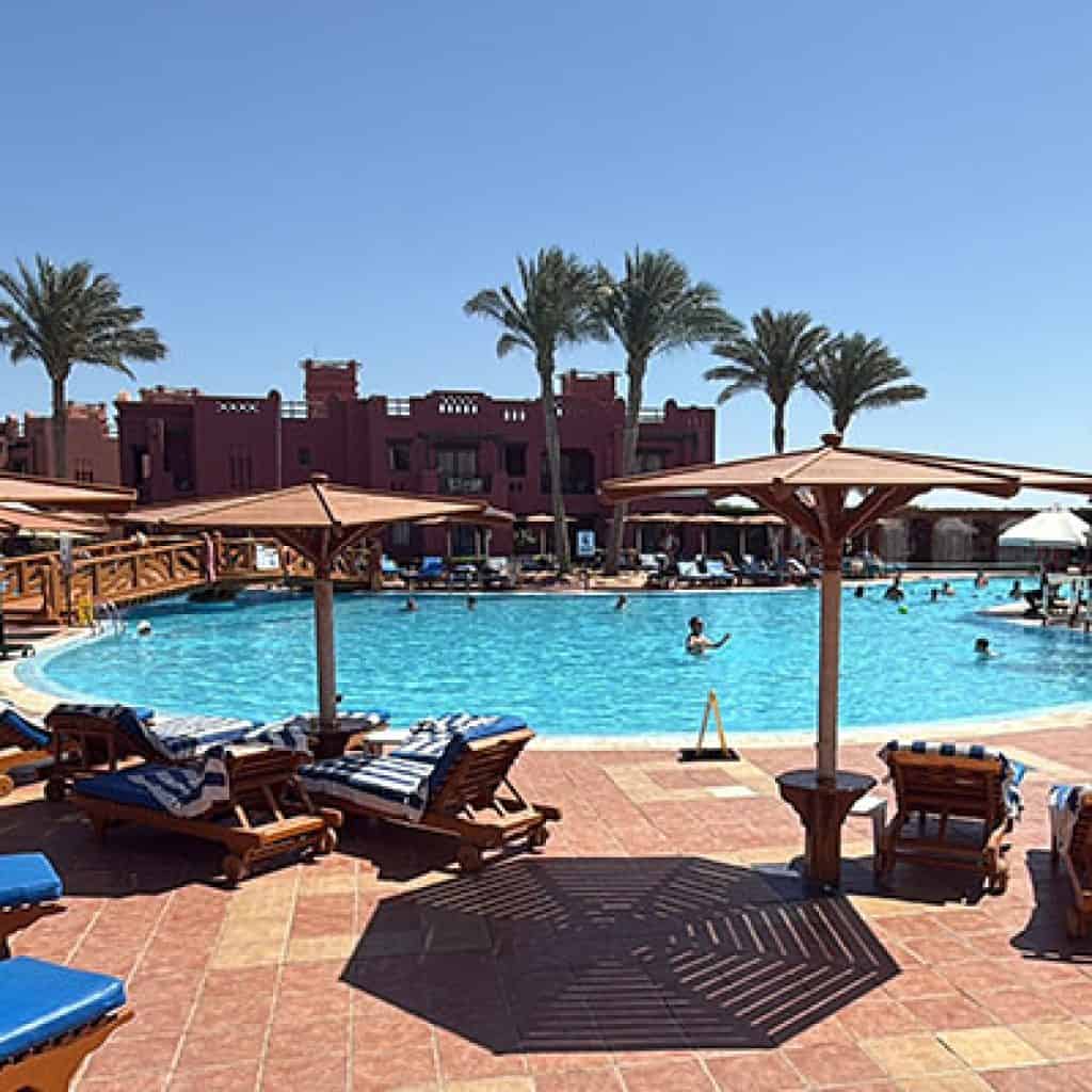 piscina dello charmillion club con lettini, ombrelloni e persone che si rilassano in piscina